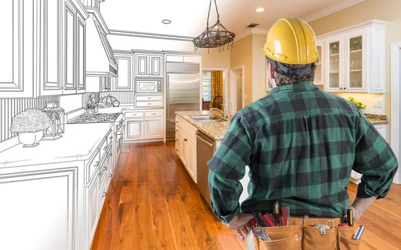 Contractor in a hard hat looking at a kitchen that is half drawing and half finished room