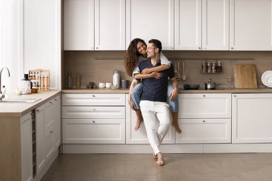 Happy homeowners together in their newly remodeled white kitchen