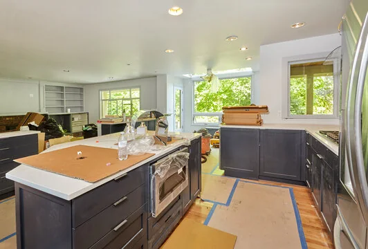 Kitchen remodel in progress with navy cabinets installed and floors protected