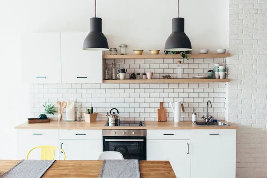 White kitchen with subway tile, open wood shelves and black pendant lights